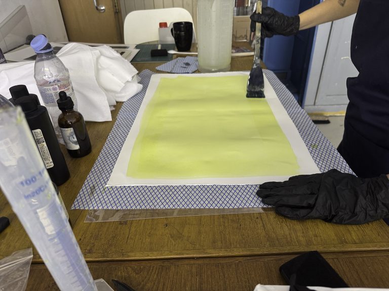 client cotting paper with cyanotype Client coating paper with cyanotype solution during a workshop